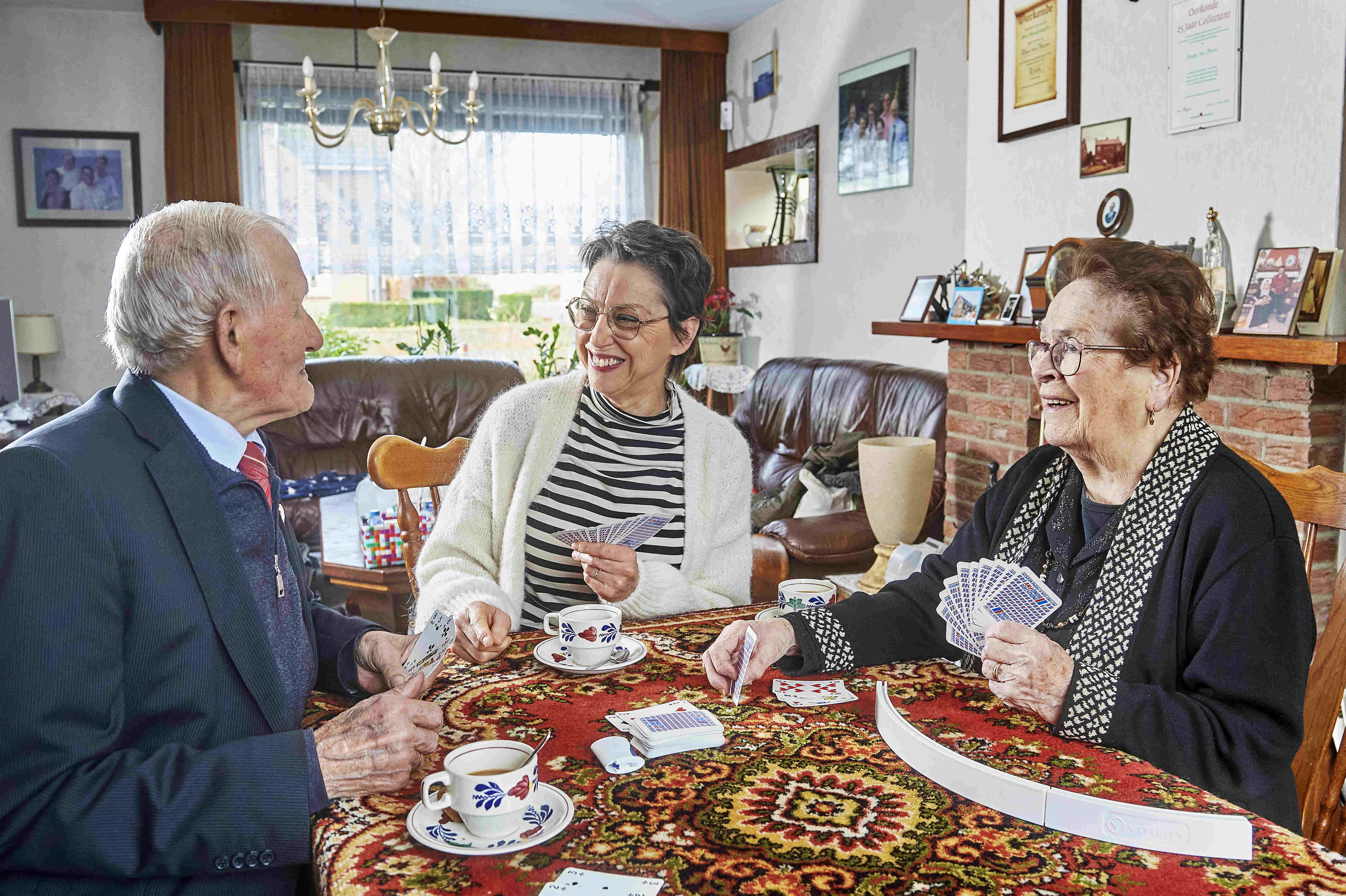 medewerker van gezelschap en ondersteuning speelt een kaartspel met meneer en mevrouw 